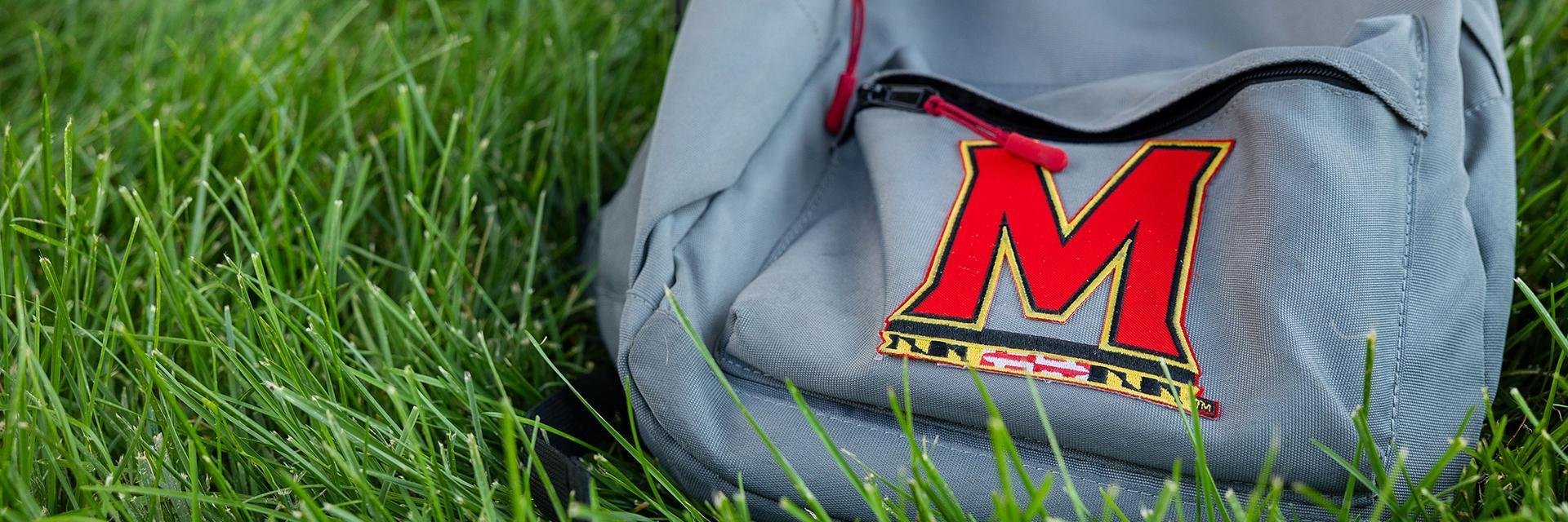 backpack with M logo on grass